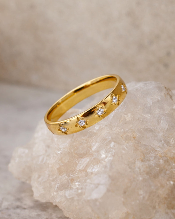 gold gemstone ring star set band angled view on natural stone surface