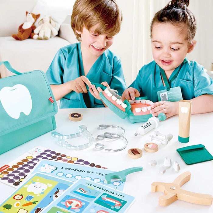 Children playing with the Hape toy dental set on a white table