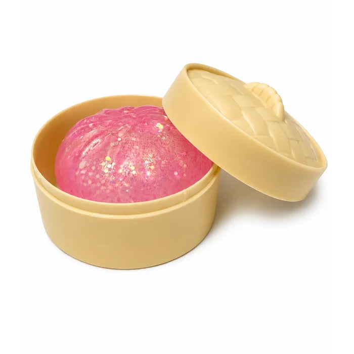 A pink glittery squishy dumpling inside a beige container with a matching lid, shown on a white background.