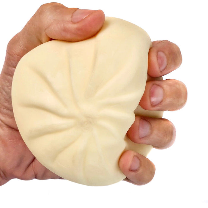 A hand squeezing a pale beige, dough-like dumpling against a plain white background.