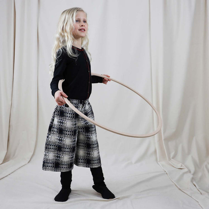 Girl wearing wide-leg tartan culottes while playing with a hula hoop