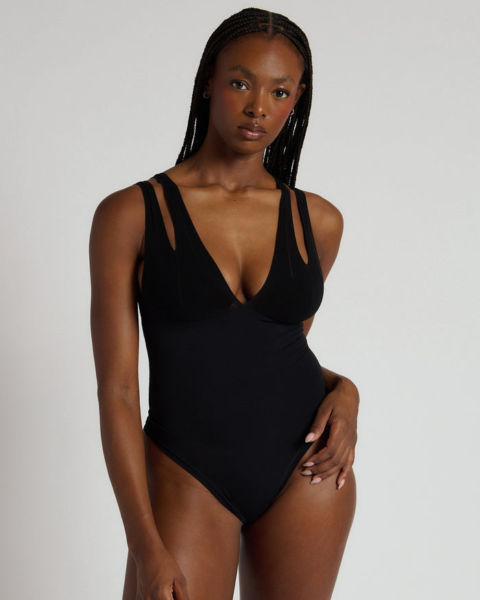 Woman wearing a black bodysuit against a plain background
