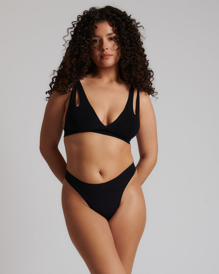 Woman wearing black tee system against a neutral background