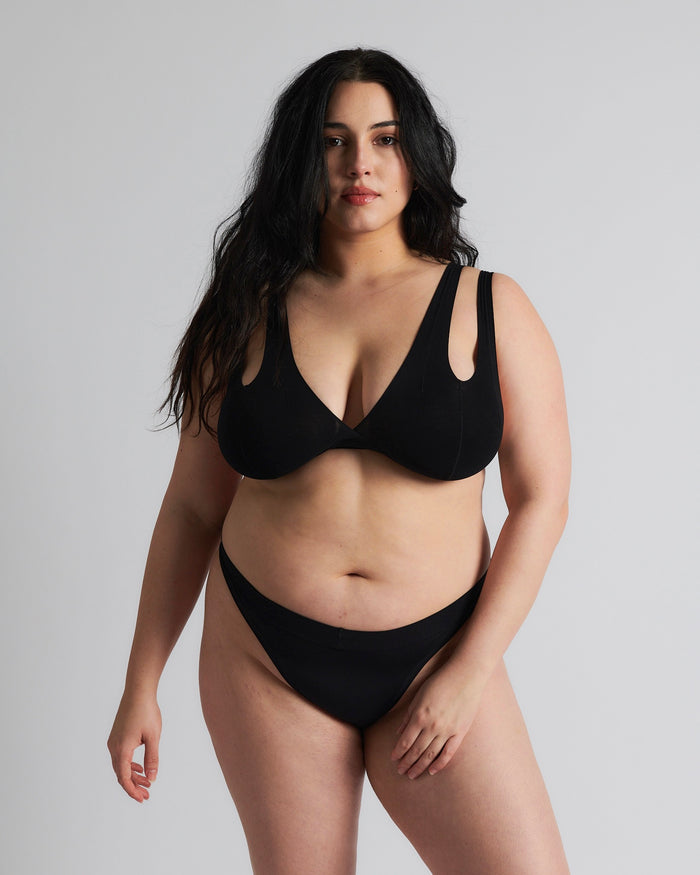 A woman is wearing a black tee system and thong