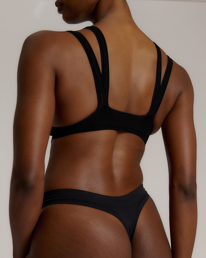 Woman wearing black tee system on plain background