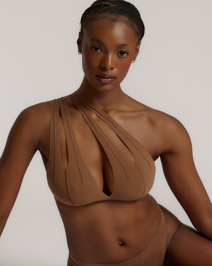 Woman wearing a brown bra against a neutral background