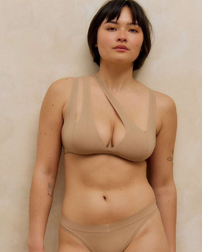 Woman wearing a light tee system and matching thong against a plain background.