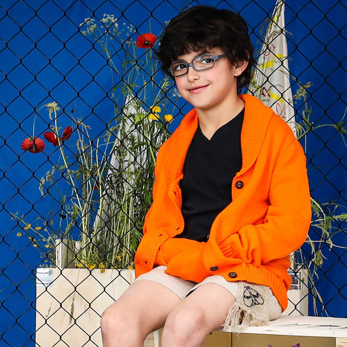 Child wearing an orange everyday cardigan over a Black shirt