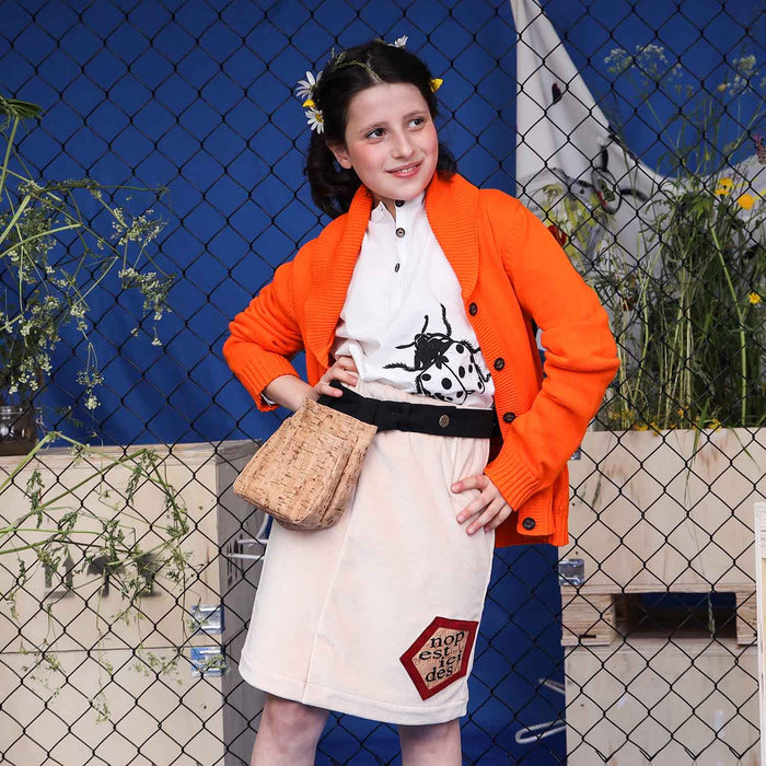 Girl wearing an orange everyday cardigan over a white shirt and skirt