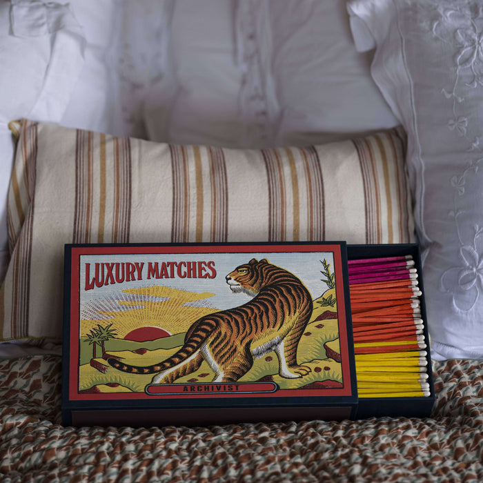 The Tiger | Giant - Safety Matches displayed on a bed with colorful matchsticks and decorative pillows.