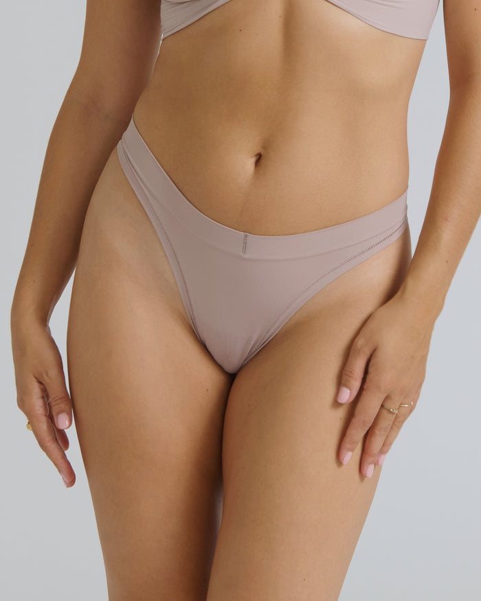Woman wearing a dusk thong on a neutral background