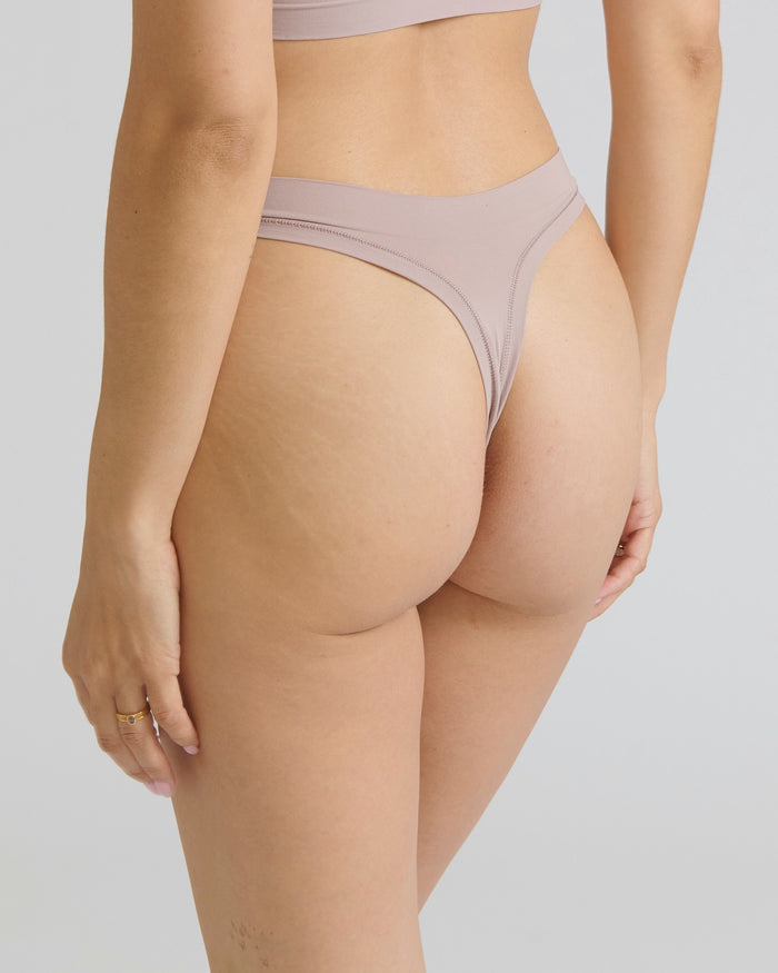 Woman wearing a dusk thong on a neutral background