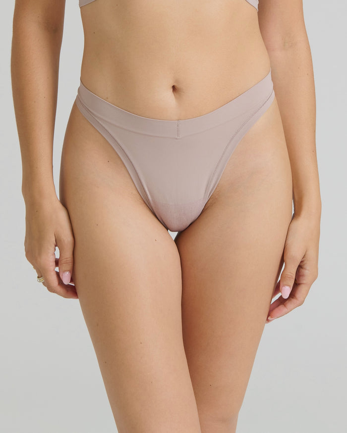 Woman wearing a dusk thong on a neutral background