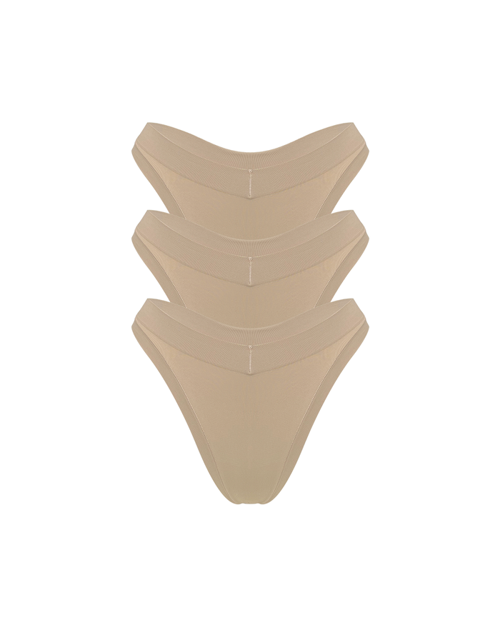 Three stacked nude beige thong underwear stacked on a solid white background.