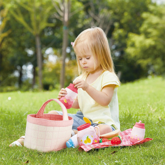 Child playing with a picnic set on grass in a park