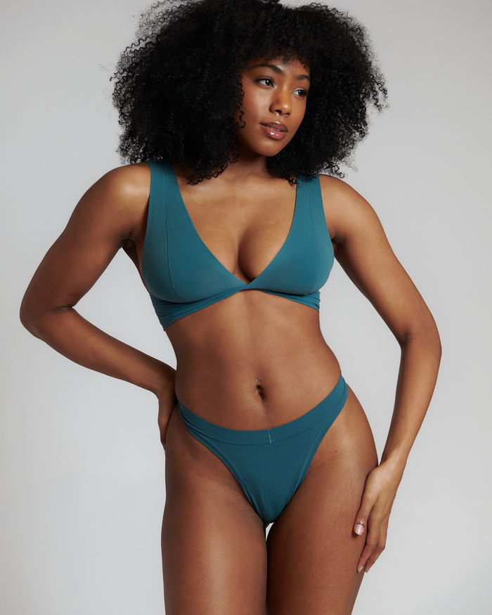 A person wearing a jade green Twist System bra with a wide band and single straps