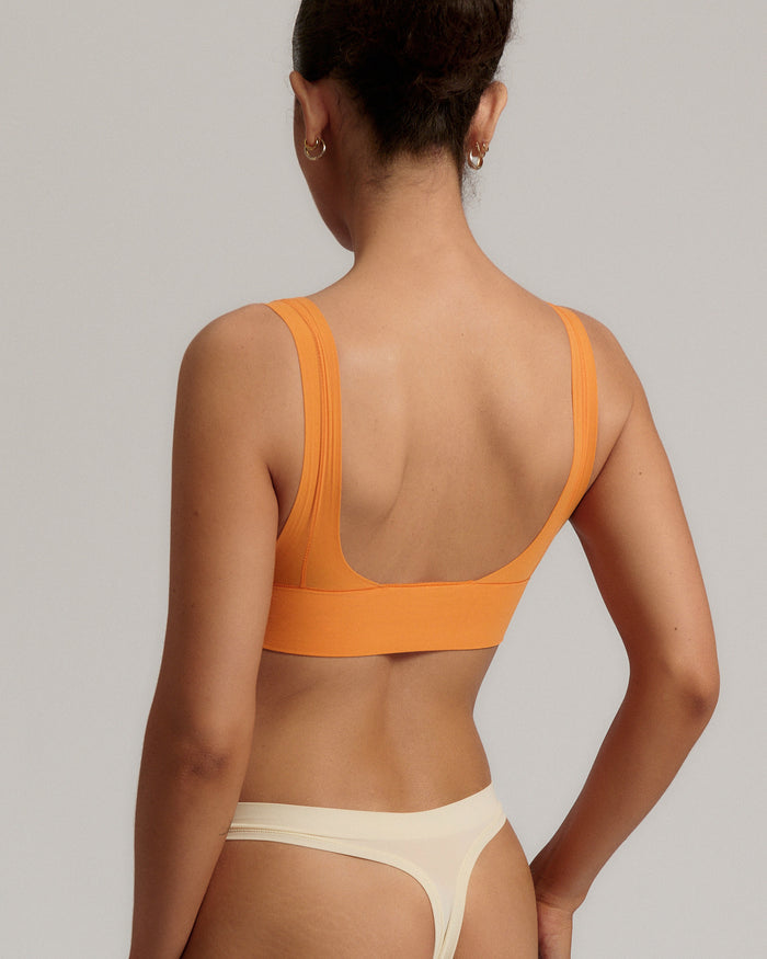 Woman wearing an orange nuudii on a plain background