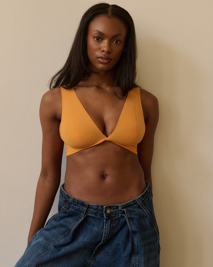 Woman wearing an orange nuudii on a plain background