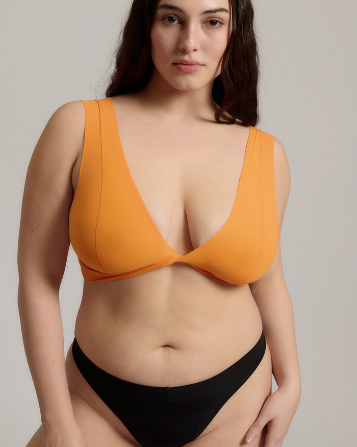 Woman wearing an orange nuudii on a plain background