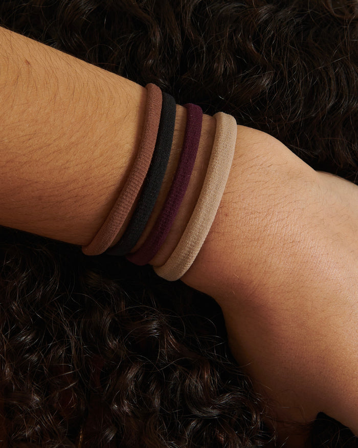A person's hand displaying various upcycled hair ties in assorted colors.