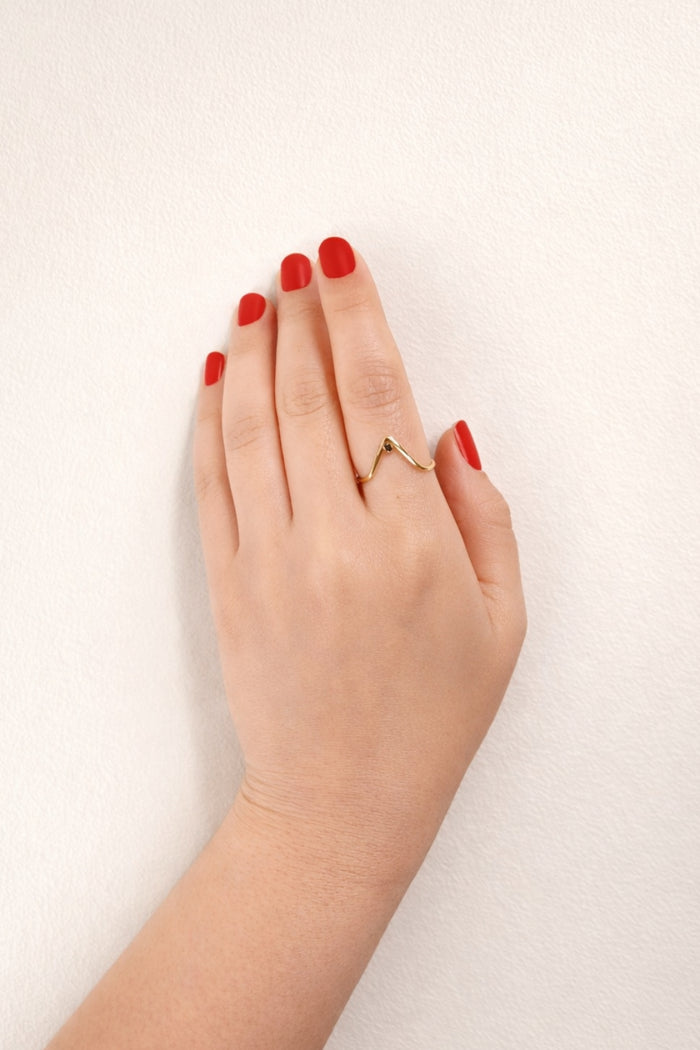 v-shaped black onyx gold ring on hand with red nails lifestyle view
