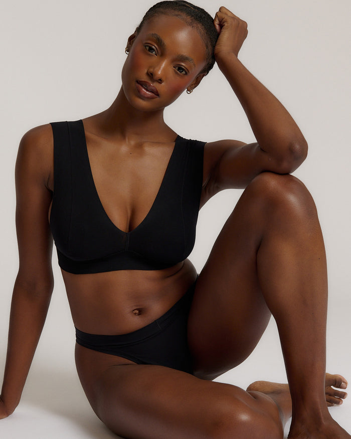 A woman wearing a black vii system with wide straps and a deep neckline.