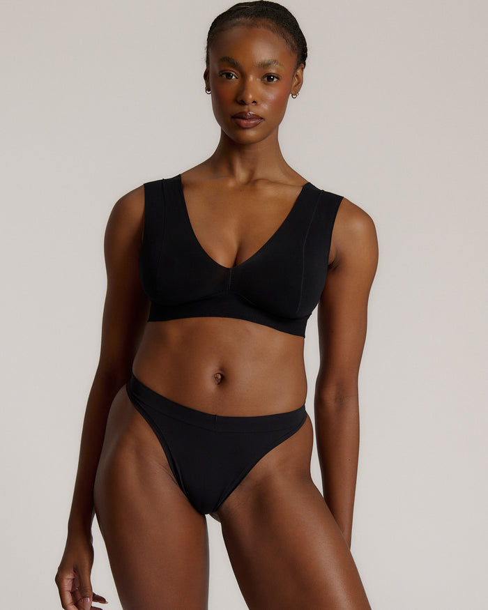A woman wearing a black vii system with wide straps and a deep neckline.
