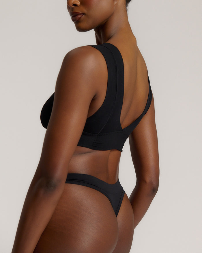 A woman wearing a black vii system with wide straps and a deep neckline.