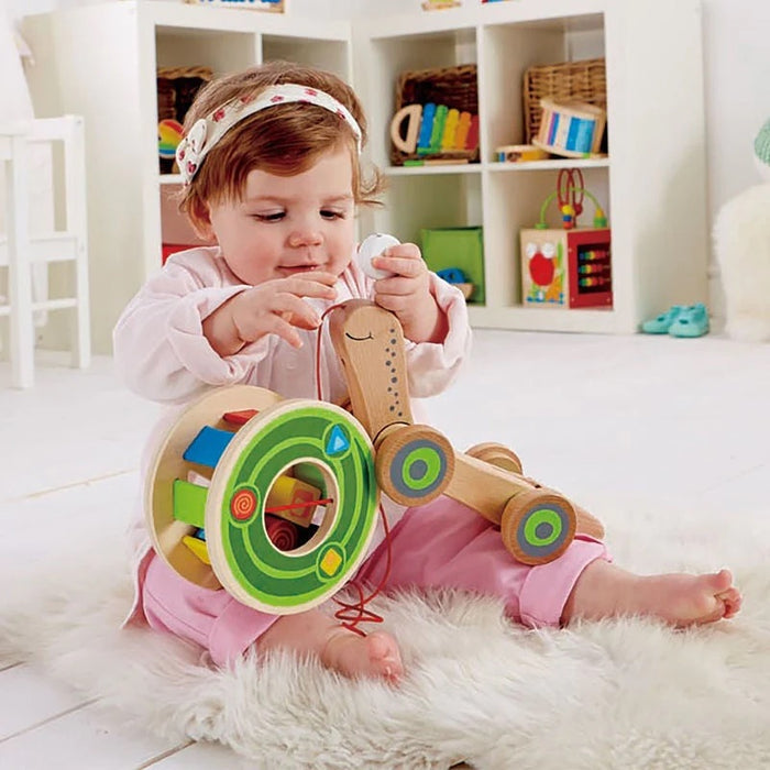 Baby playing with the walk along snail on a fuzzy rug in a playroom