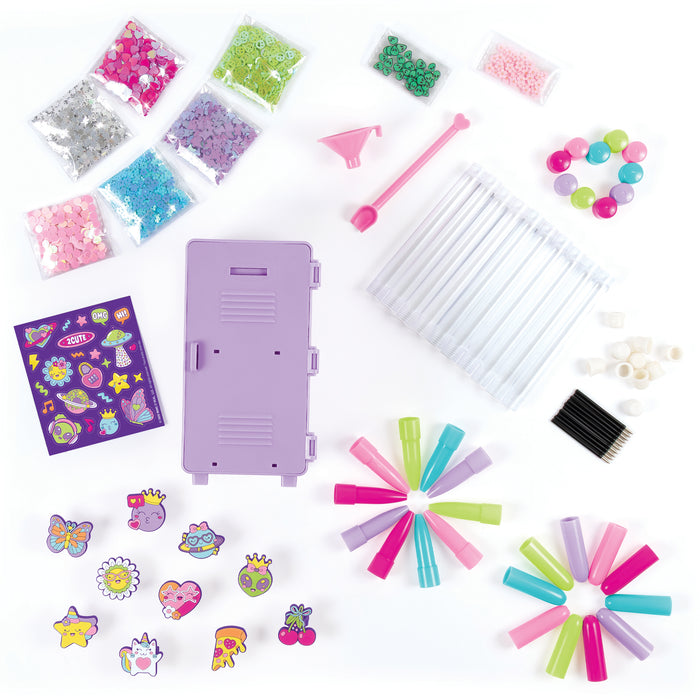A children's craft kit laid out on a white background, including a lavender plastic storage box, clear plastic tubes, colorful beads, sequins, stickers, small tools, and other craft supplies in assorted bright colors.
